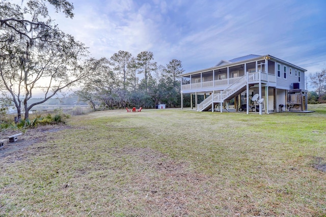 rear view of property featuring stairs, a yard, and a sunroom