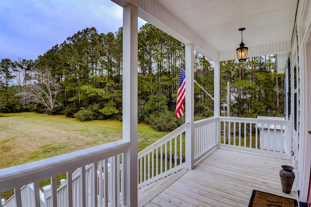 wooden terrace featuring a lawn and a porch