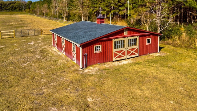 view of outbuilding with an outdoor structure, fence, and a view of trees