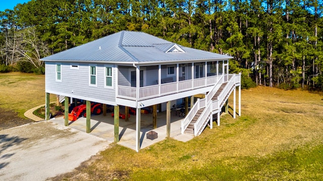 rear view of property with stairs, a carport, and dirt driveway