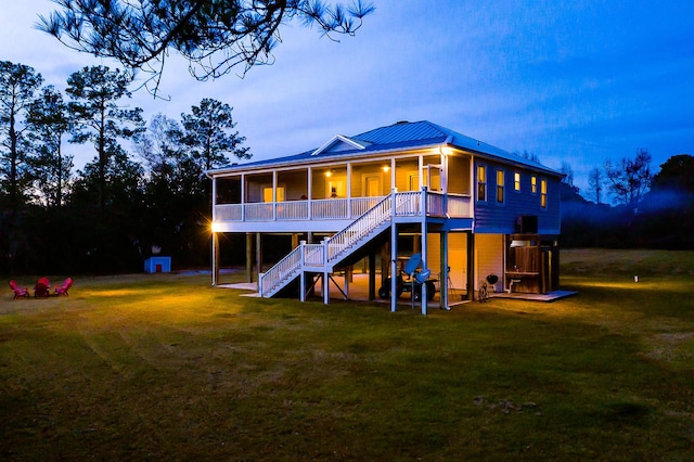 back of property featuring metal roof, stairs, a yard, and a sunroom