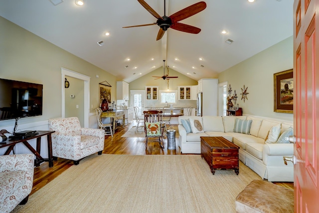 living room with ceiling fan, wood finished floors, visible vents, and high vaulted ceiling