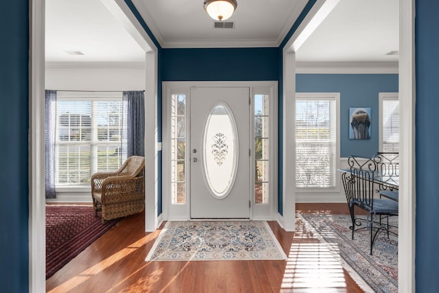 entrance foyer featuring crown molding, wood finished floors, and visible vents