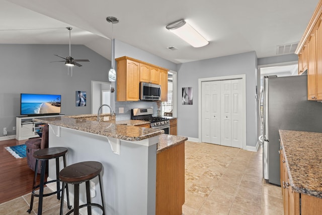 kitchen featuring visible vents, a ceiling fan, appliances with stainless steel finishes, a breakfast bar area, and a peninsula