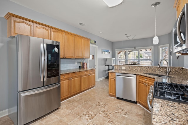 kitchen with light stone counters, visible vents, a sink, decorative backsplash, and appliances with stainless steel finishes