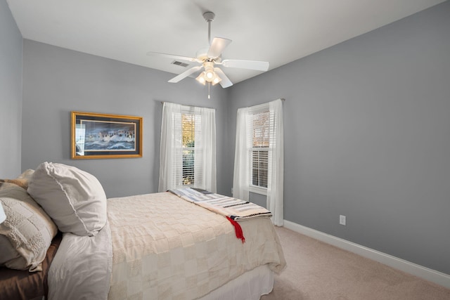 bedroom featuring visible vents, light colored carpet, baseboards, and ceiling fan