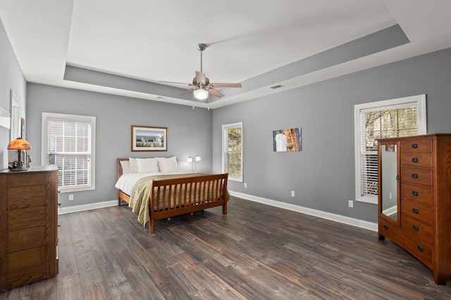 bedroom featuring dark wood finished floors, a raised ceiling, and baseboards