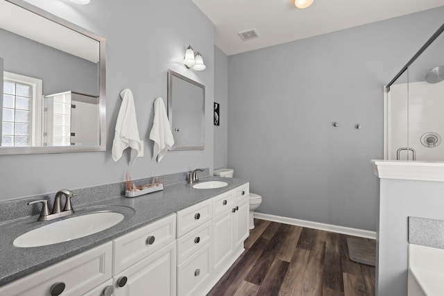 full bathroom with a shower with shower door, wood finished floors, visible vents, and a sink