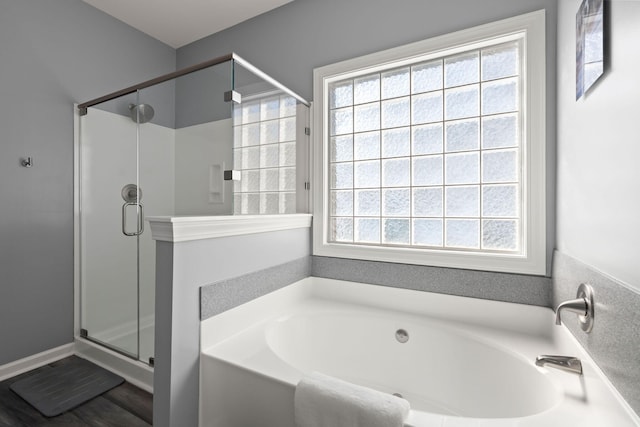 bathroom with plenty of natural light, a garden tub, and a shower stall