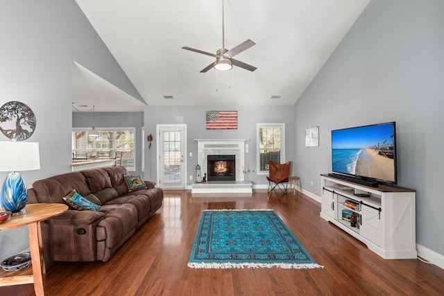 living area with wood finished floors, high vaulted ceiling, ceiling fan, and a fireplace