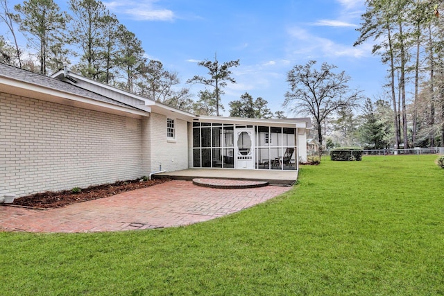 back of property featuring a patio, fence, a sunroom, a lawn, and brick siding