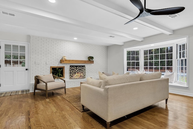 living room featuring beamed ceiling, visible vents, a ceiling fan, wood finished floors, and a fireplace