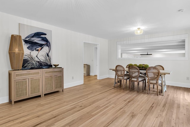 dining area featuring baseboards and light wood finished floors