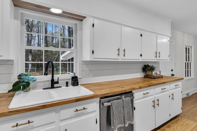 kitchen featuring a sink, wood counters, dishwasher, and white cabinetry