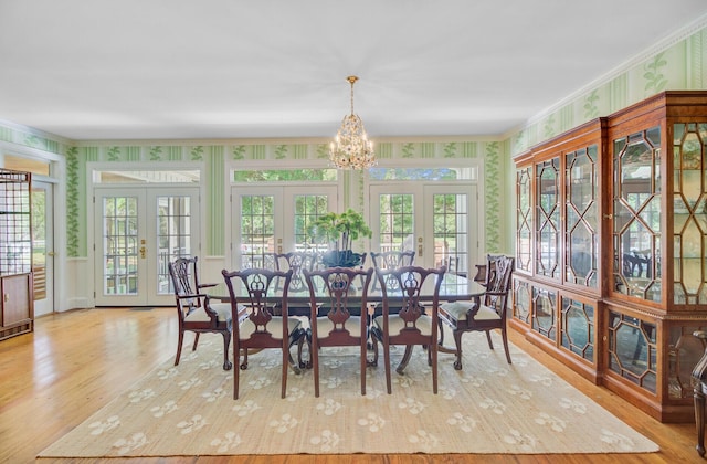 481 Cantey Ln, Camden, SC 29020 - dining room with wallpapered walls, french doors, a chandelier, wood finished floors, and crown molding