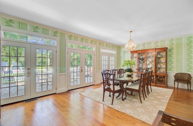 481 Cantey Ln, Camden, SC 29020 - dining space featuring french doors, wallpapered walls, a chandelier, wood finished floors, and a wainscoted wall