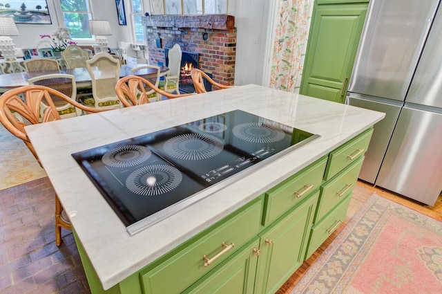 481 Cantey Ln, Camden, SC 29020 - kitchen featuring green cabinetry, freestanding refrigerator, black electric stovetop, and a brick fireplace