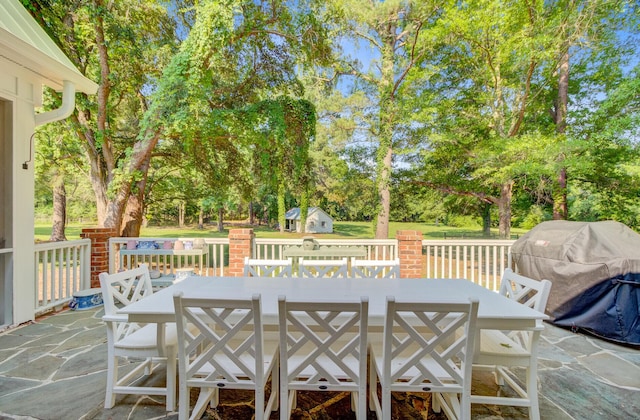 481 Cantey Ln, Camden, SC 29020 - deck with outdoor dining area, view of scattered trees, a patio, and an outbuilding