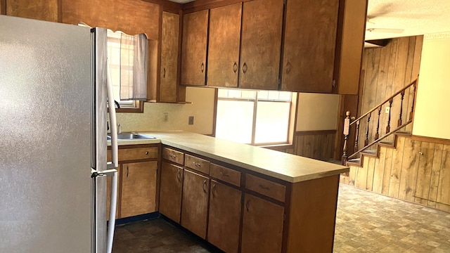 kitchen with dark tile patterned floors, white refrigerator, kitchen peninsula, and ceiling fan