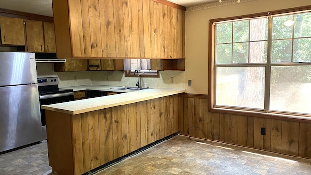 kitchen featuring appliances with stainless steel finishes, sink, kitchen peninsula, exhaust hood, and tile patterned floors