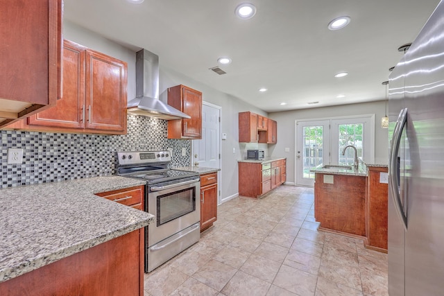 kitchen featuring brown cabinetry, a sink, wall chimney range hood, stainless steel appliances, and tasteful backsplash