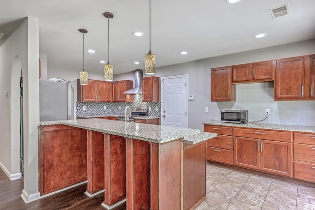 kitchen featuring light stone countertops, recessed lighting, visible vents, wall chimney range hood, and appliances with stainless steel finishes