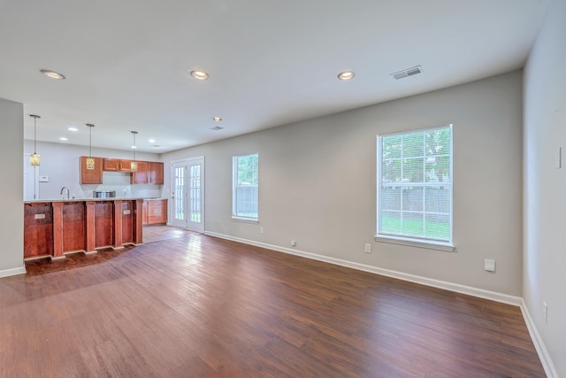 unfurnished living room with baseboards, dark wood-type flooring, visible vents, and recessed lighting