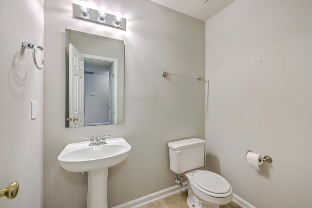 bathroom featuring a sink, toilet, baseboards, and tile patterned floors