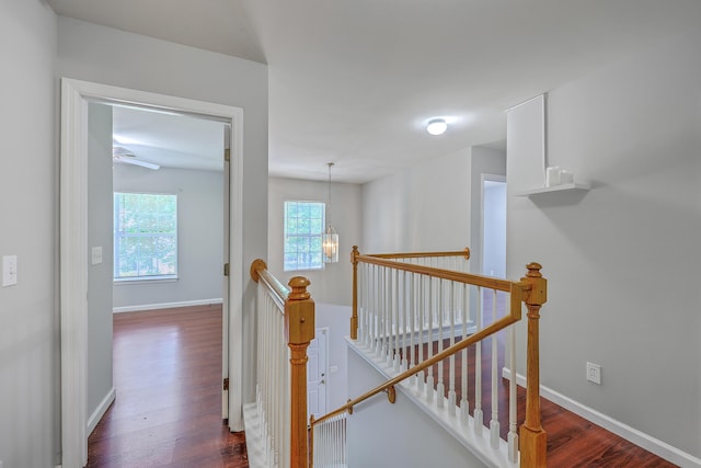 hallway featuring dark wood finished floors, an upstairs landing, and baseboards