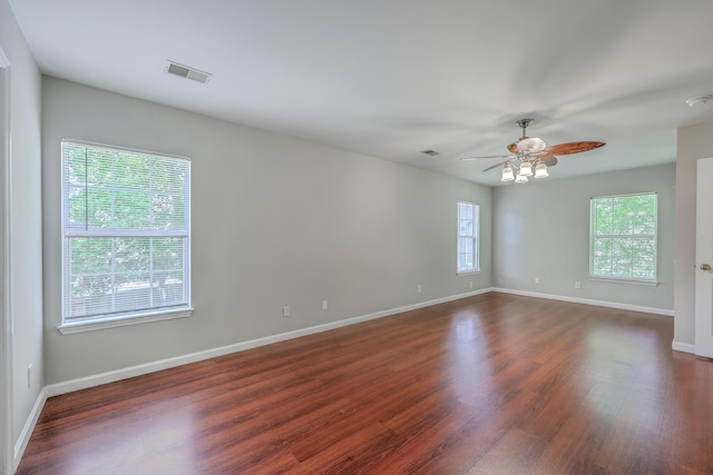 spare room with baseboards, a ceiling fan, and dark wood finished floors
