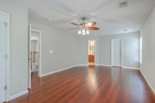 interior space with baseboards, a ceiling fan, visible vents, and dark wood-type flooring