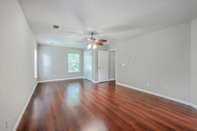spare room featuring baseboards, visible vents, dark wood-style flooring, and a ceiling fan
