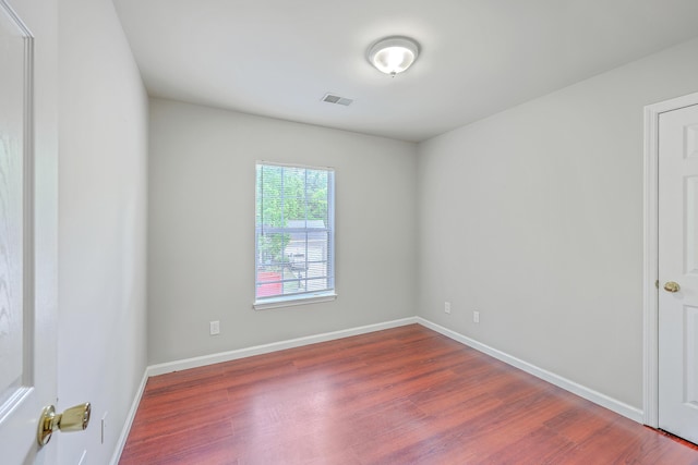 unfurnished room with visible vents, wood finished floors, and baseboards