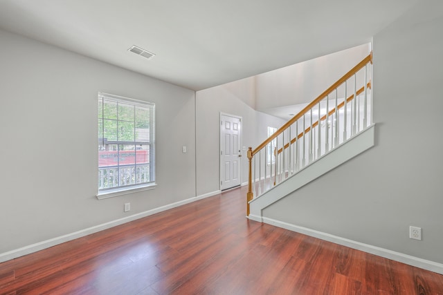 foyer entrance featuring visible vents, wood finished floors, baseboards, and stairs