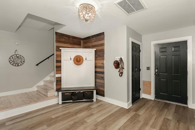 entrance foyer with visible vents, stairway, wood walls, wood finished floors, and baseboards