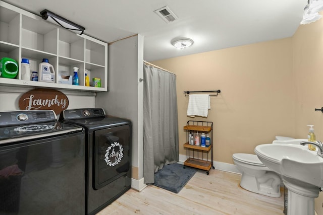 washroom with visible vents, separate washer and dryer, light wood-type flooring, laundry area, and baseboards