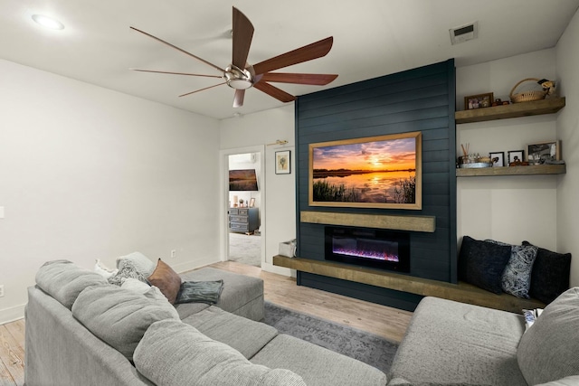 living room with visible vents, baseboards, light wood-style flooring, ceiling fan, and a fireplace