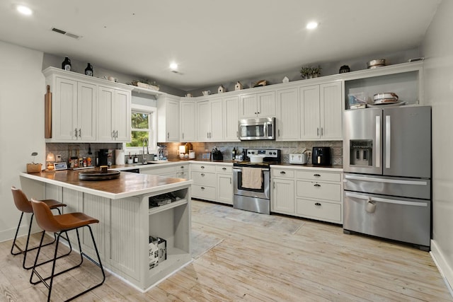 kitchen with visible vents, white cabinets, a peninsula, stainless steel appliances, and open shelves