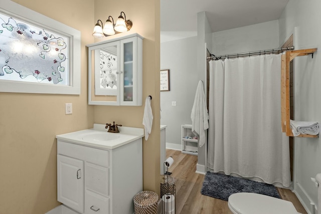 bathroom featuring toilet, curtained shower, wood finished floors, and vanity