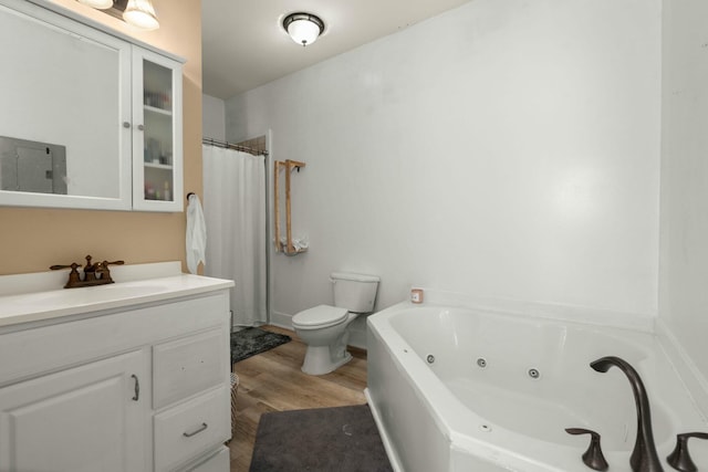 bathroom with a whirlpool tub, vanity, toilet, and wood finished floors