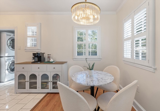 dining space featuring light wood-type flooring, stacked washing maching and dryer, crown molding, and a wealth of natural light