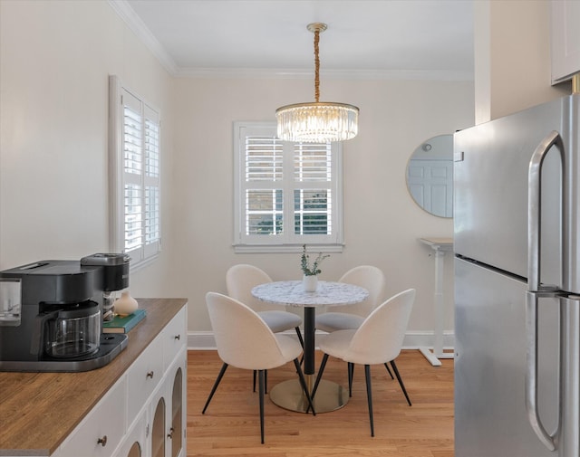 dining room featuring a chandelier, light hardwood / wood-style flooring, and crown molding