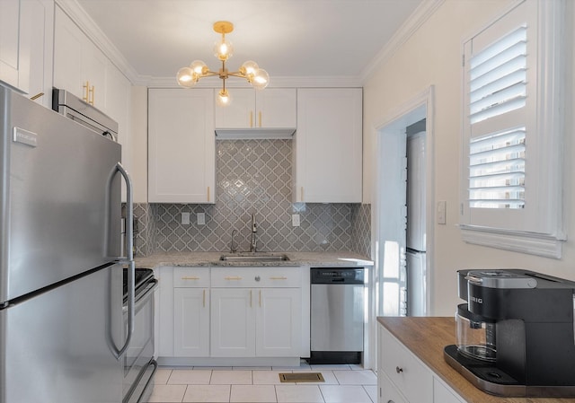 kitchen with sink, appliances with stainless steel finishes, light tile patterned flooring, white cabinetry, and a chandelier