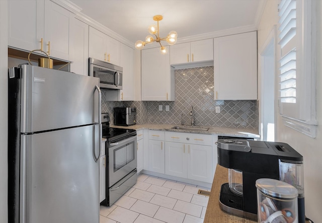 kitchen featuring light stone counters, stainless steel appliances, sink, white cabinetry, and hanging light fixtures