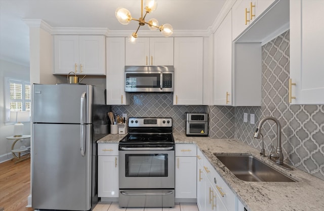 kitchen with white cabinets, decorative light fixtures, stainless steel appliances, and sink