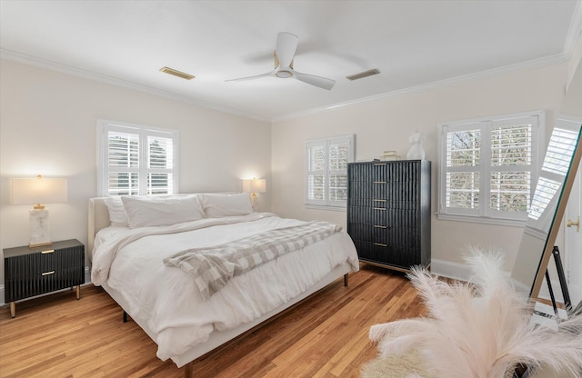 bedroom featuring multiple windows, ceiling fan, light hardwood / wood-style flooring, and ornamental molding