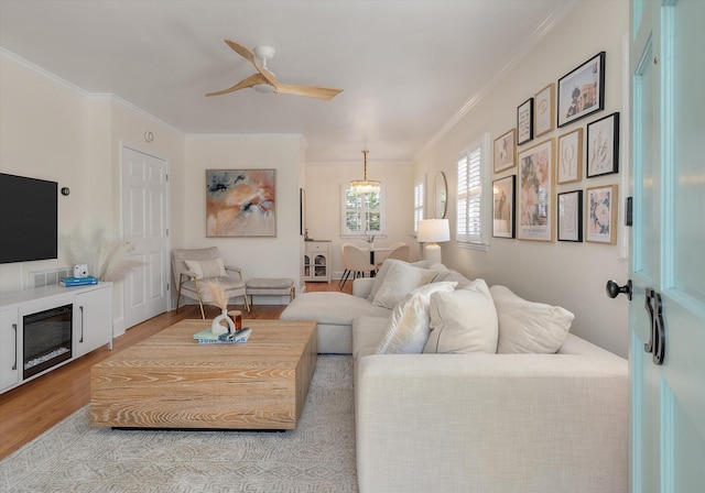 living room with light wood-type flooring, ceiling fan, and ornamental molding