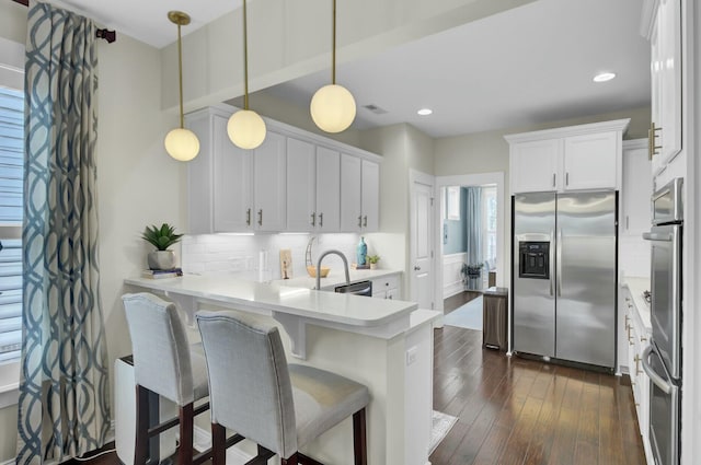 kitchen featuring stainless steel refrigerator with ice dispenser, kitchen peninsula, white cabinets, and decorative light fixtures