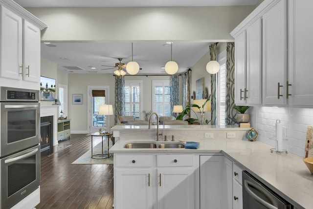 kitchen featuring sink, white cabinetry, appliances with stainless steel finishes, kitchen peninsula, and backsplash