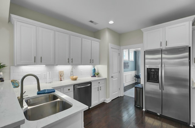 kitchen with sink, white cabinetry, dark hardwood / wood-style flooring, stainless steel appliances, and decorative backsplash